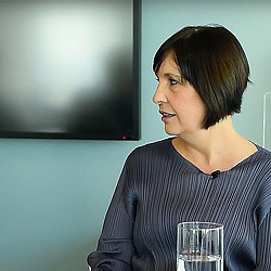 A woman smiling and looking at a glass.