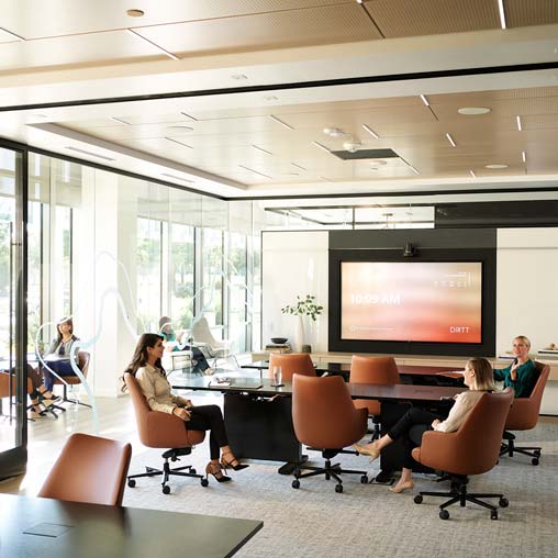 A group of people sitting in a room with a large screen.
