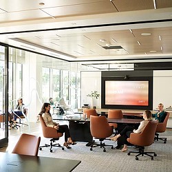 A group of people sitting in a room with a large screen.