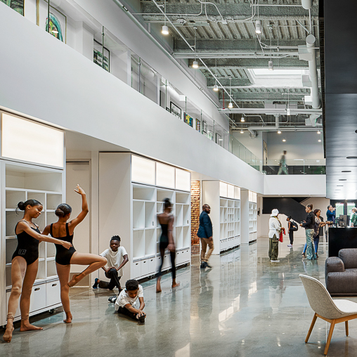 A group of people dancing in a room with white walls and a ceiling.