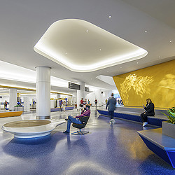 A group of people sitting in chairs in a large room with a large yellow wall and a large.