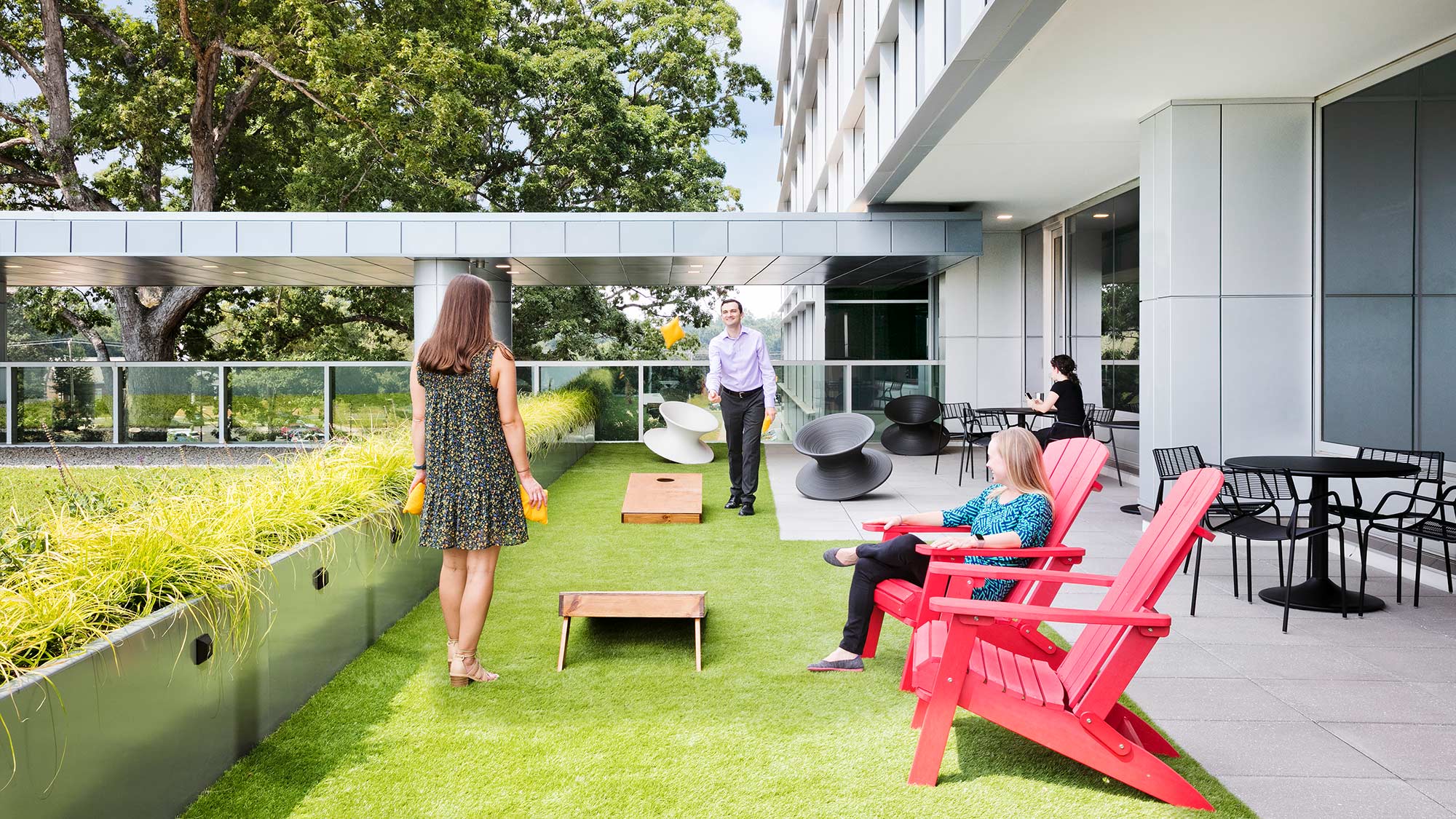 Employees playing cornhole on outdoor workplace terrace