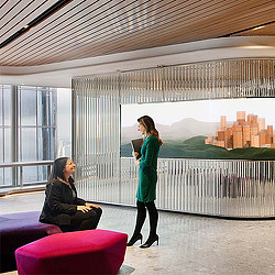A woman standing in front of a window looking at a woman sitting on a pink couch.