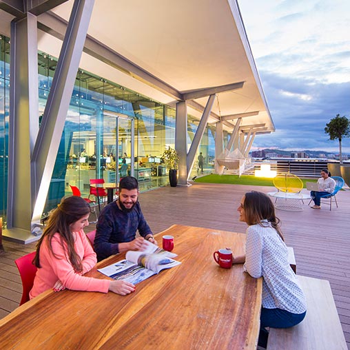 3 employees gathered around outdoor table at Gensler Costa Rica.