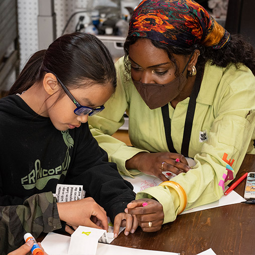 Volunteer helping girl with craft project at Chapter 510 Swan's Market.