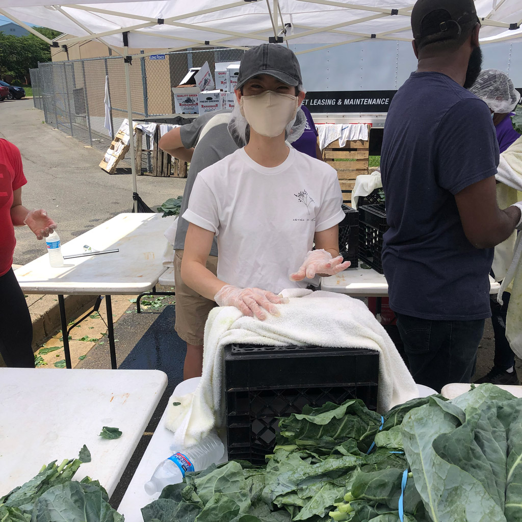 A person selling vegetables at an outdoor market.