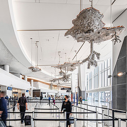 A group of people walking with luggage through an airport ticketing terminal.