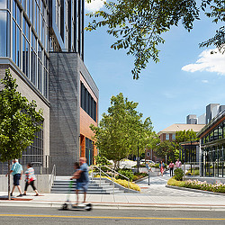 Two people on electric scooter riding along Bloc[83] Tower II street