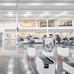 A person in a white coat standing next to several white machines.