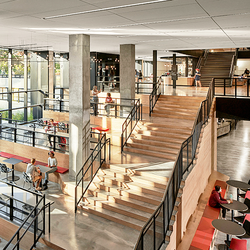 A modern wooden staircase with seating across multiple levels at Kentucky University Commons Helm Library