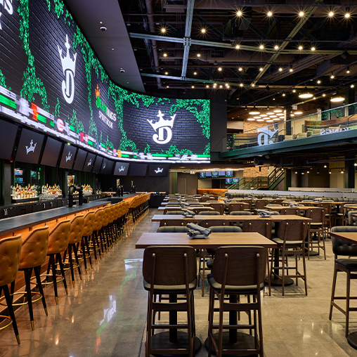 A large sports entertainment venue at DraftKings Sportsbook interior with large screens and a bar