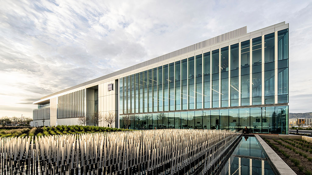 A large glass building with a fountain in front of it.