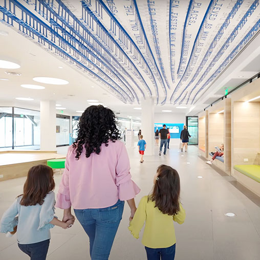 Mother and 2 daughters holding hands walking into Frisco Public Library