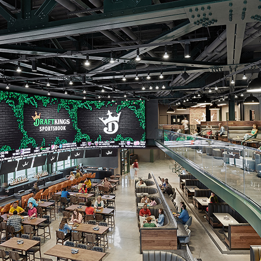 A large sports entertainment venue at DraftKings Sportsbook interior with large screens and a bar