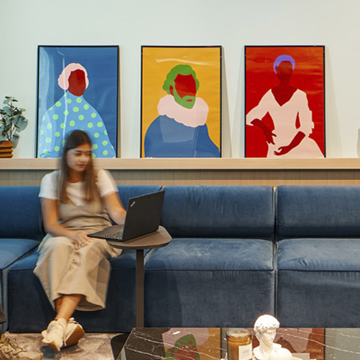 Woman sitting on blue couch in McCann Worldgroup workspace with colorful paintings