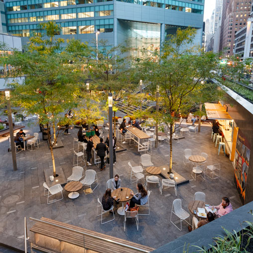 A group of people sitting at tables outside.