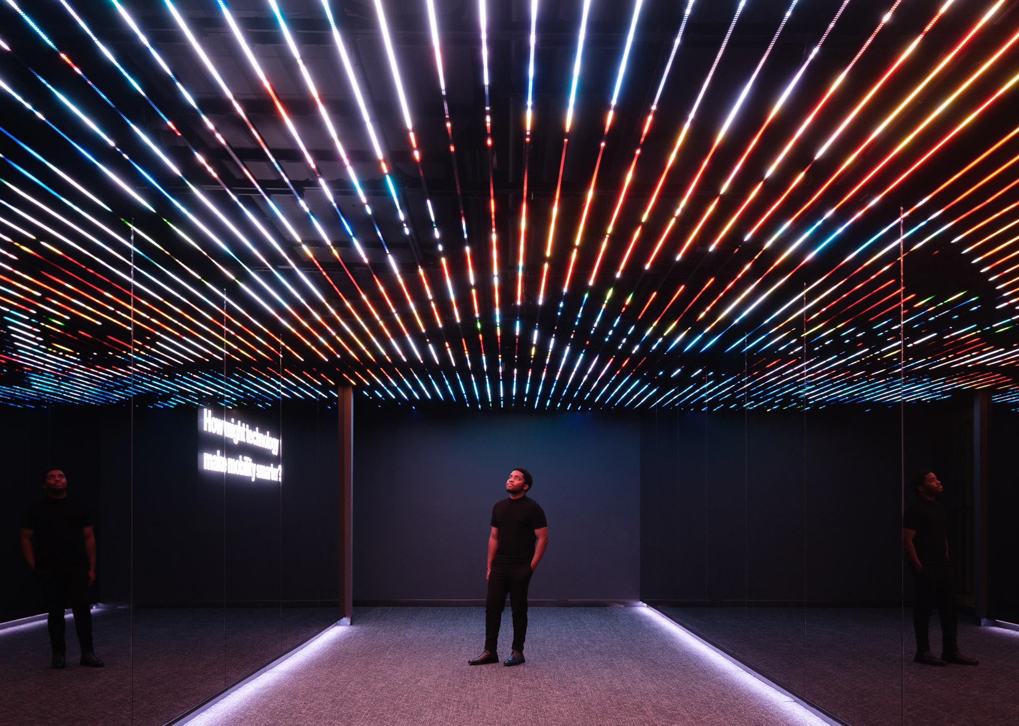 A group of people standing in a room with a stage and lights.