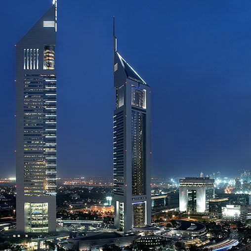 A couple of tall buildings with lights on at night.