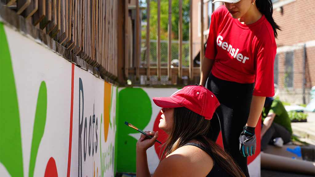 Two Gensler team members painting Roots to Success mural
