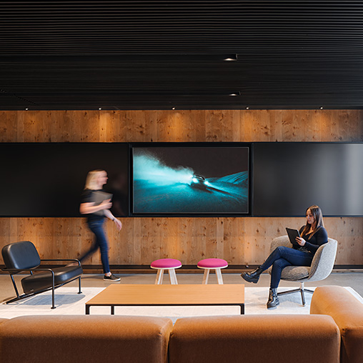 A person standing in front of a screen at a new Denver media company office.