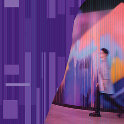 A person standing in front of a wall with colorful squares.