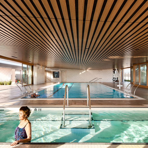 A person sitting on a balcony above a swimming pool.
