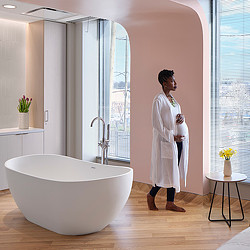 A person in a white coat in a bathroom.