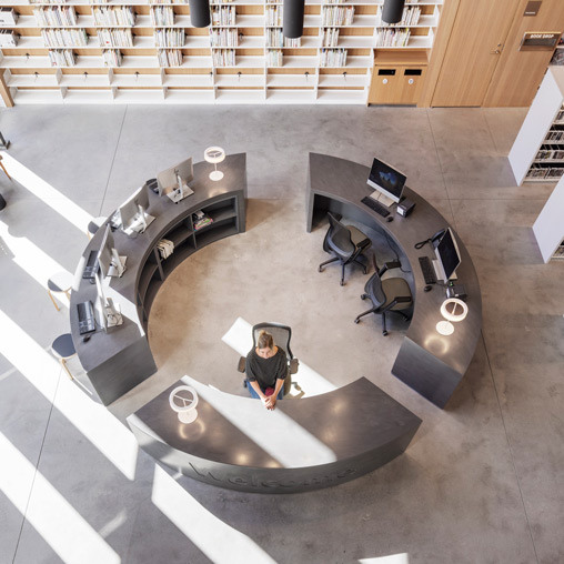 A person standing in a room with a large circular table and chairs.