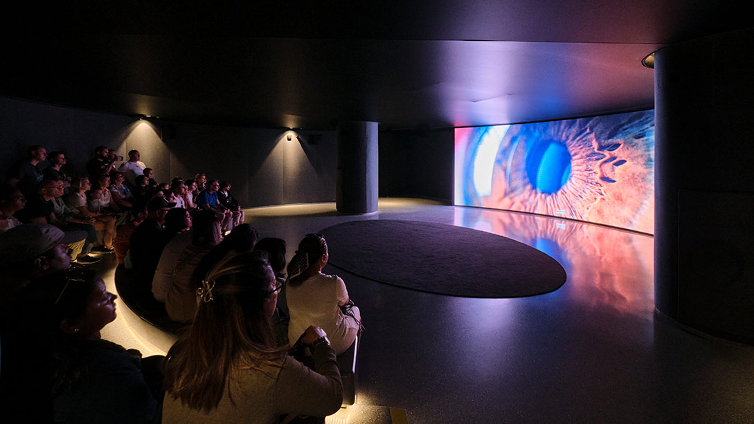 A group of people sitting in a room with a large screen.