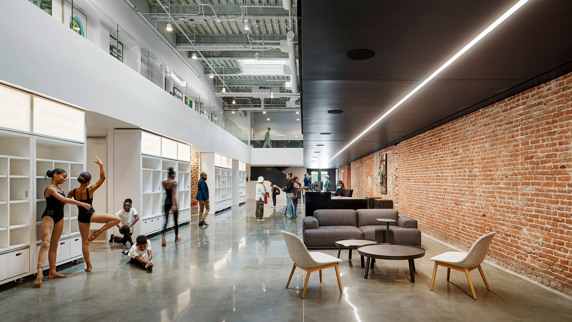 People in a room with a brick wall and a couch.