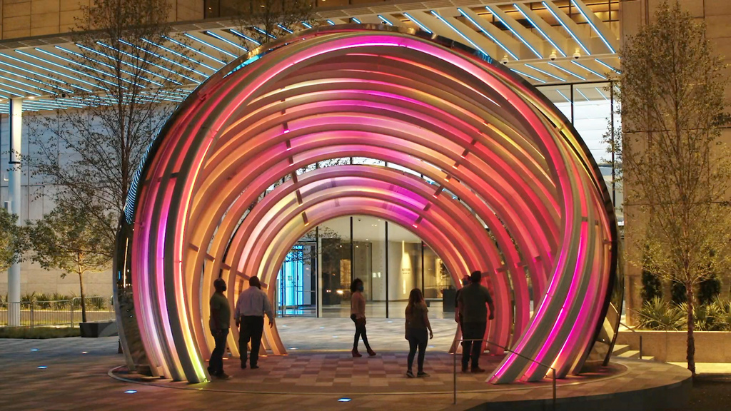 People walking under a large arch.