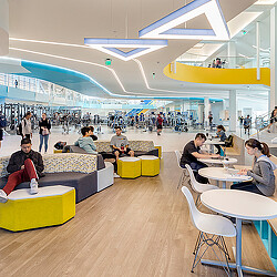 A group of people sitting in a room with tables and chairs.