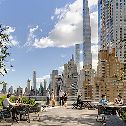 A group of people sitting on benches in a city.