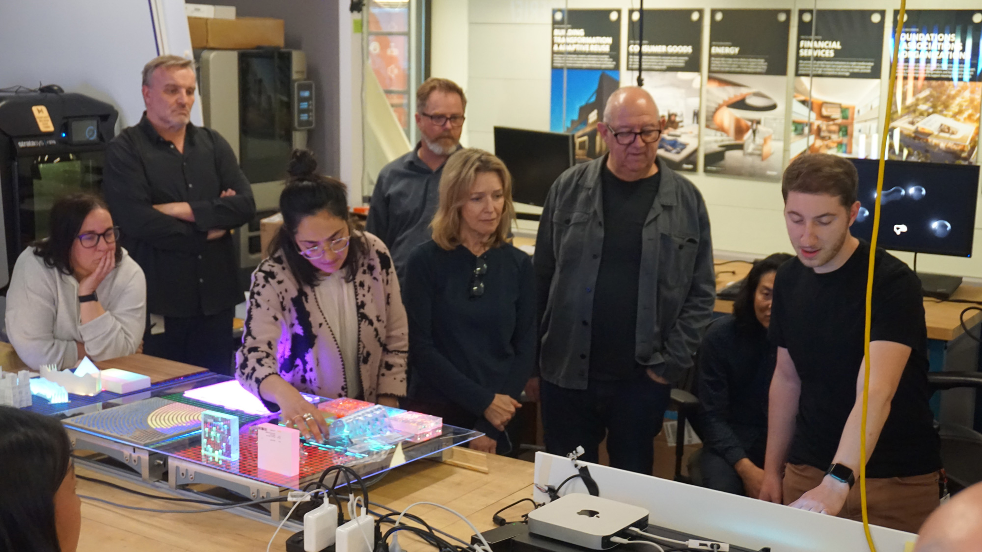 A group of people standing around a table with a model of a train.