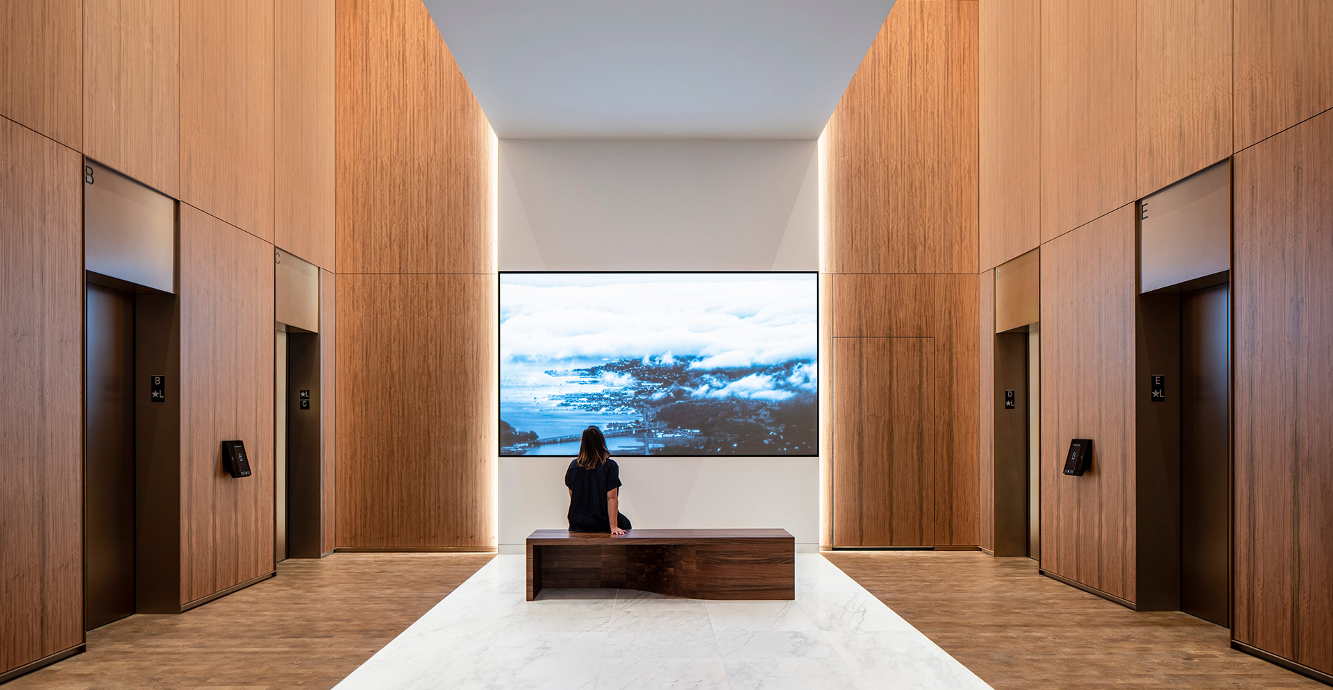 A person sitting on a bench in a room with wood walls.