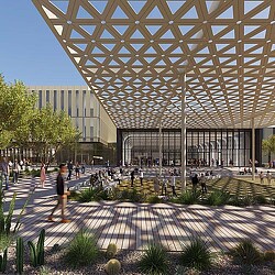 A large glass building with a courtyard and people walking around.