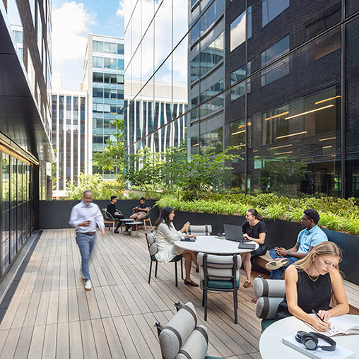 A group of people sitting at tables outside.