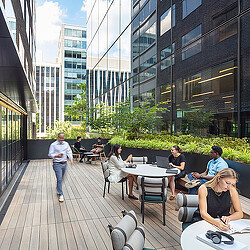 A group of people sitting at tables outside.