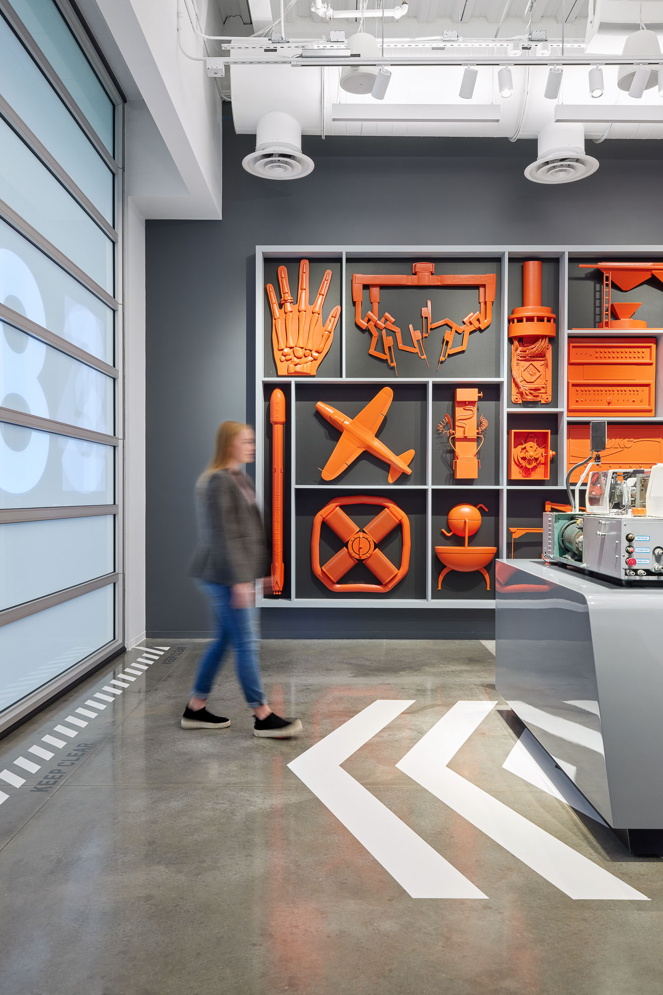 A woman walking in The Smart Factory by Deloitte space with orange figures on the wall