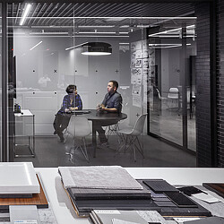 A man and woman sitting at a table in a room with glass walls.