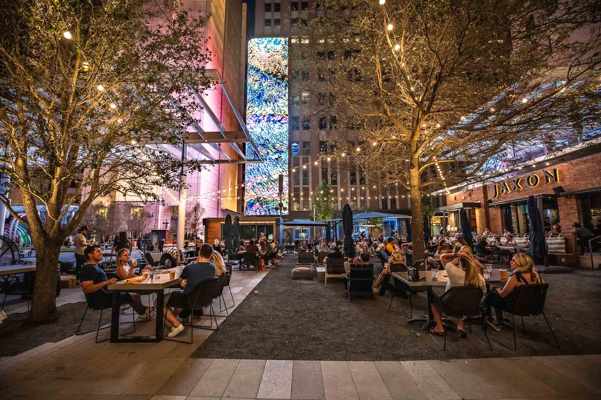 A group of people sitting at tables in a city.