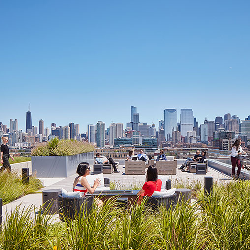 A group of people sitting at tables in front of a city.