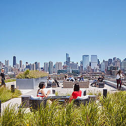 A group of people sitting at tables in front of a city.