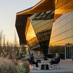 A couple of people sitting on a bench outside of a building.