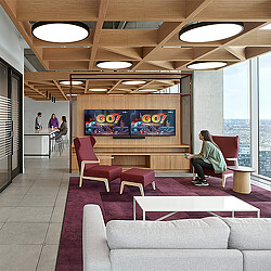 A person sitting on a bench in a room with a large screen.