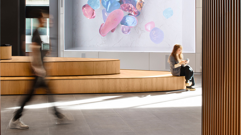 A person sitting on a bench in front of a large screen.
