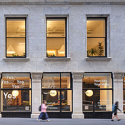 A building with windows and people walking by.