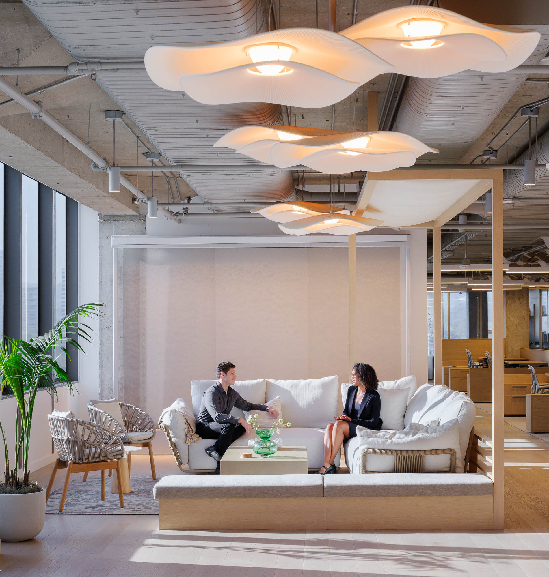 A man and woman sitting on a couch in a room with wavy light fixtures