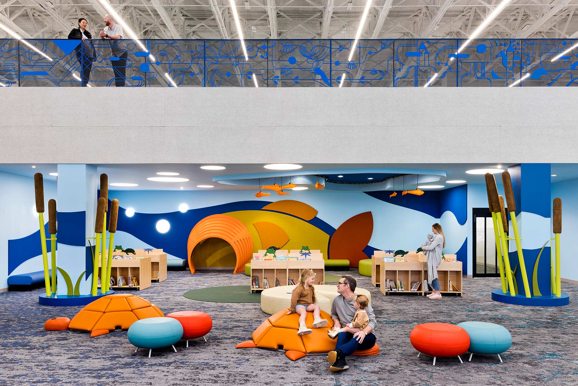 A group of people sitting on a couch in a room with a large colorful slide.