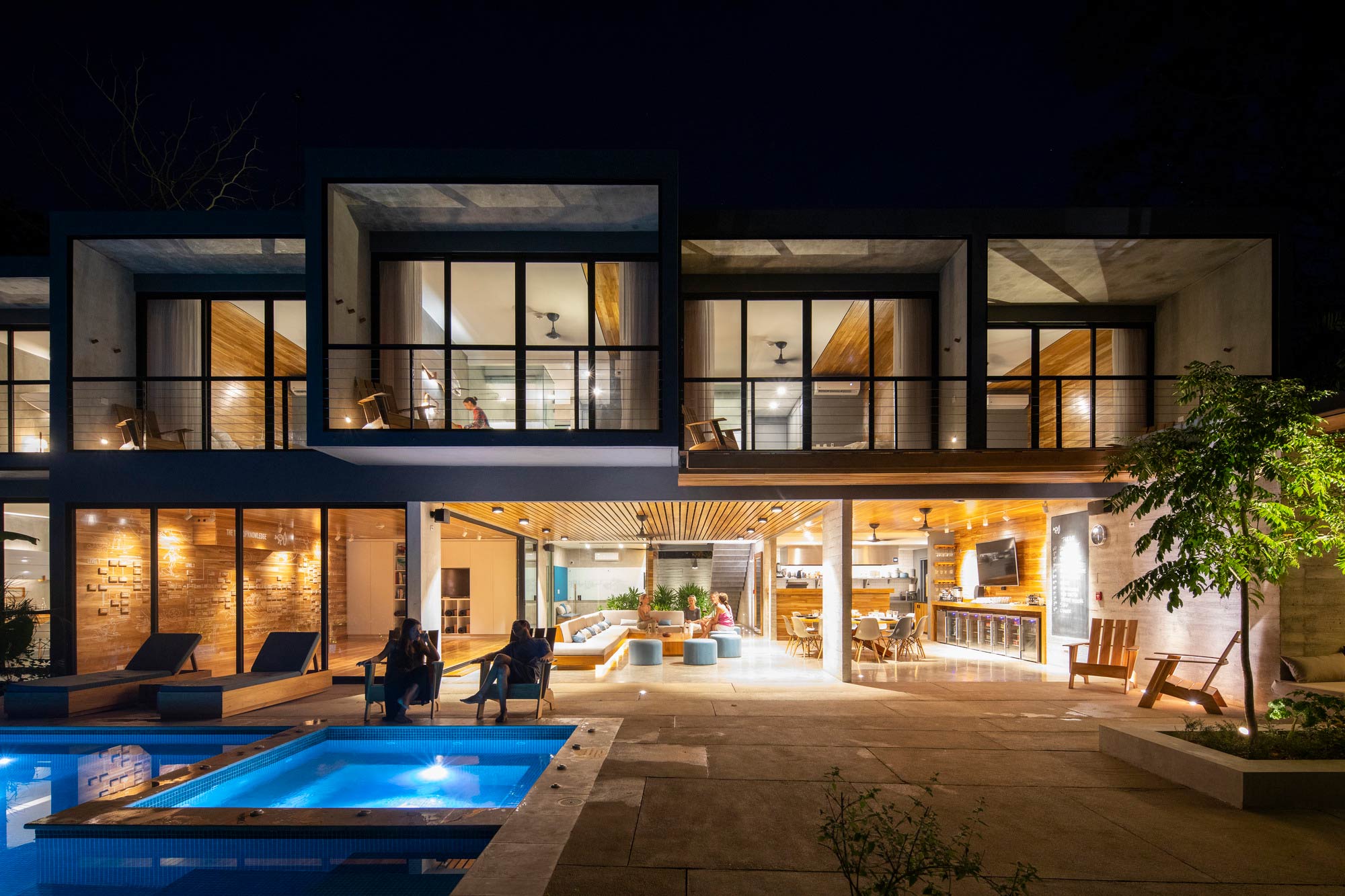 A house with a pool and a deck with a large glass wall.
